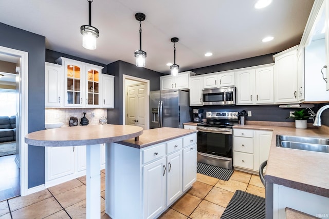 kitchen with a center island, white cabinets, sink, appliances with stainless steel finishes, and decorative light fixtures