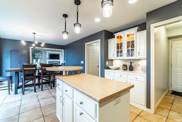 kitchen featuring pendant lighting, white cabinets, tasteful backsplash, a kitchen island, and a chandelier