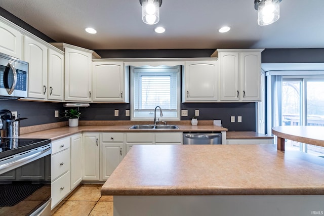 kitchen featuring white cabinets, stainless steel appliances, a kitchen island, and sink