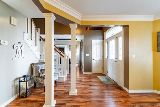 foyer entrance with a textured ceiling, dark hardwood / wood-style floors, ornate columns, and ornamental molding