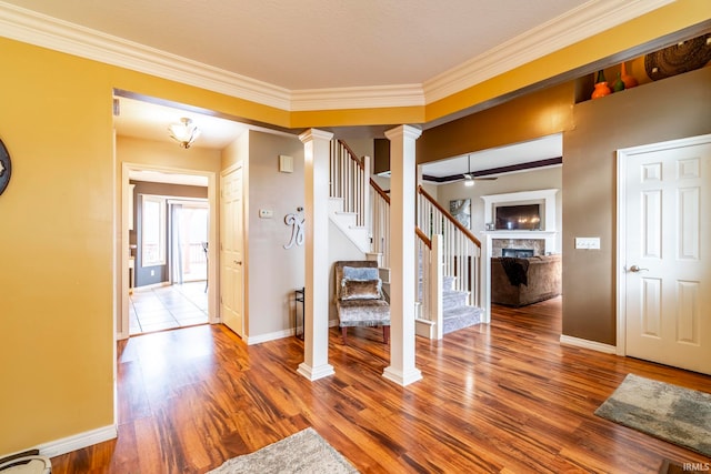 foyer featuring hardwood / wood-style floors, ornate columns, ceiling fan, and ornamental molding