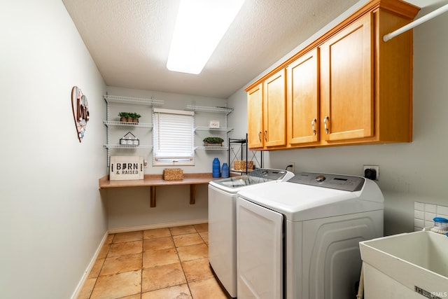 laundry room featuring sink, cabinets, a textured ceiling, light tile patterned flooring, and washer and dryer