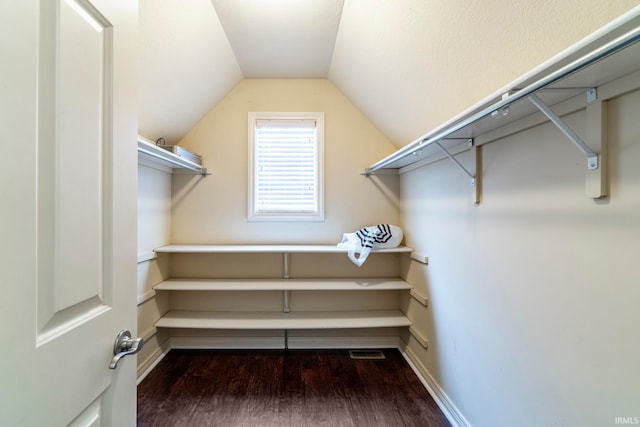 walk in closet featuring dark hardwood / wood-style floors and vaulted ceiling