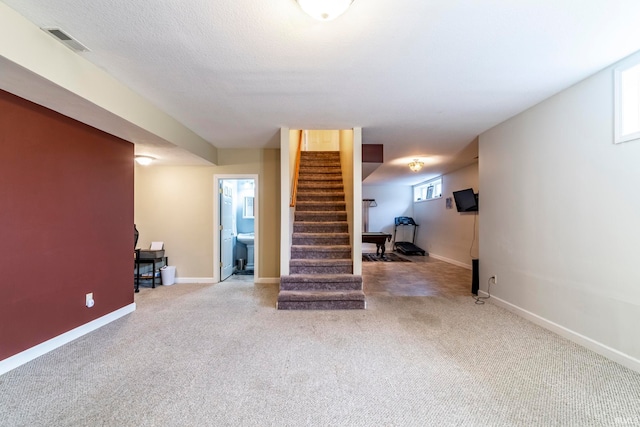 basement featuring carpet flooring, plenty of natural light, and a textured ceiling