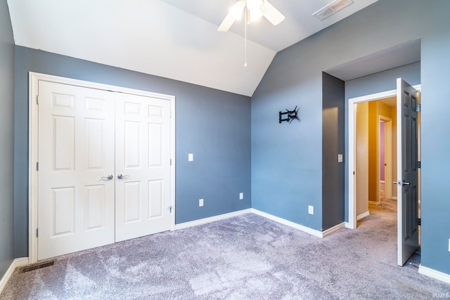 unfurnished bedroom with carpet flooring, a closet, vaulted ceiling, and ceiling fan