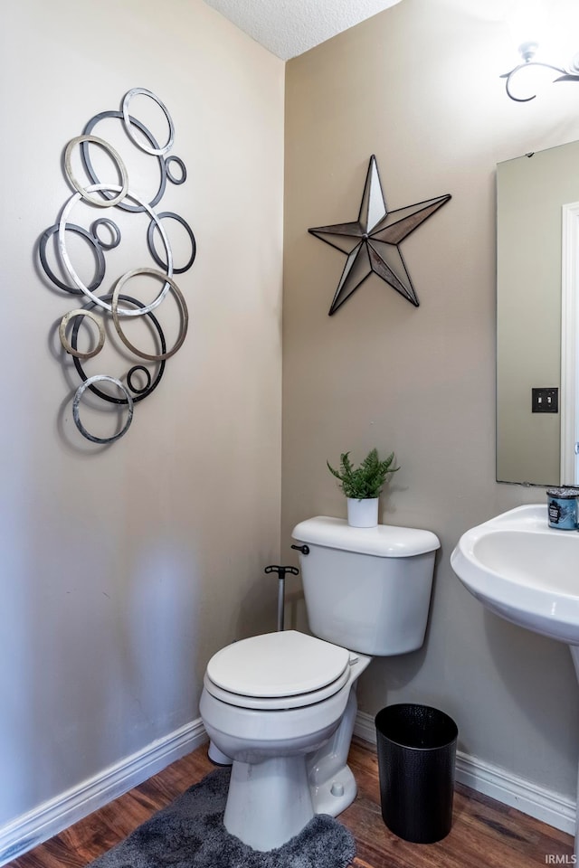 bathroom with wood-type flooring, a textured ceiling, and toilet