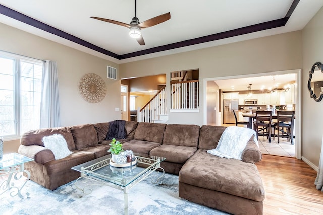 living room with ceiling fan with notable chandelier and light wood-type flooring