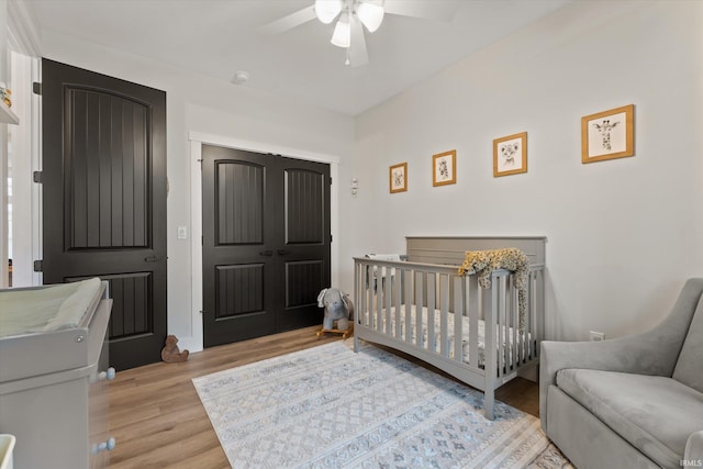 bedroom with ceiling fan, light hardwood / wood-style floors, and a crib