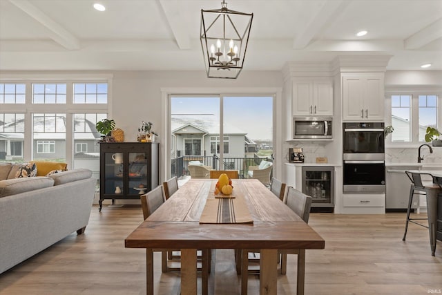 dining space with beam ceiling, light wood-type flooring, and wine cooler