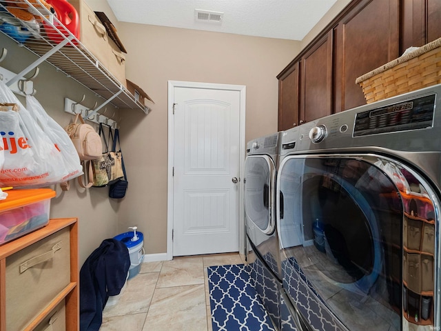 laundry room featuring separate washer and dryer, light tile patterned floors, and cabinets