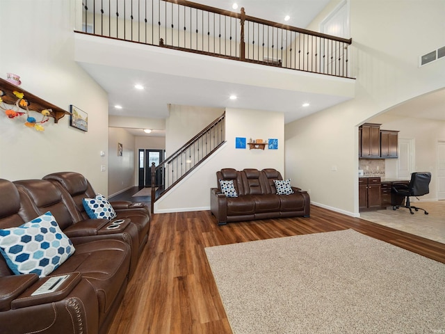 living room featuring a towering ceiling and dark wood-type flooring