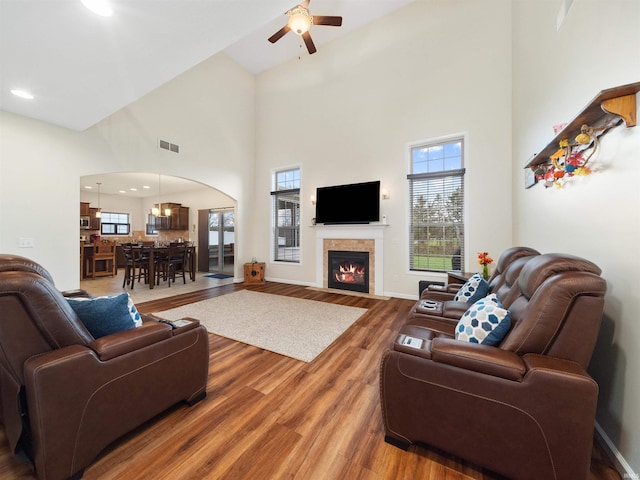 living room with ceiling fan with notable chandelier, a high ceiling, and hardwood / wood-style flooring