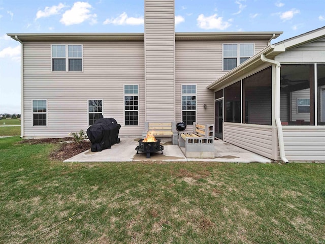 back of property with a sunroom, an outdoor fire pit, a patio, and a lawn