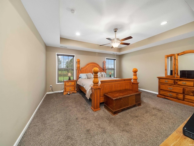 carpeted bedroom with ceiling fan and a raised ceiling