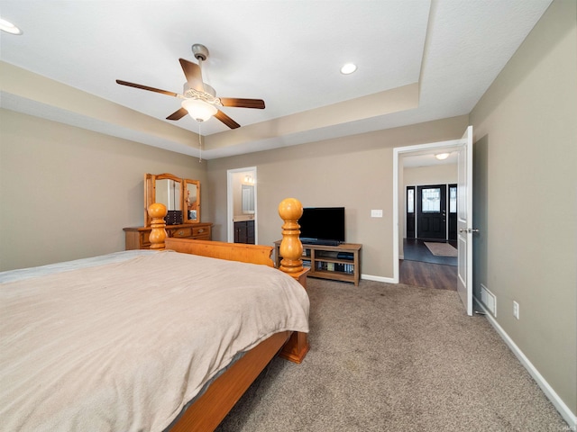 bedroom featuring dark colored carpet, a raised ceiling, and ceiling fan