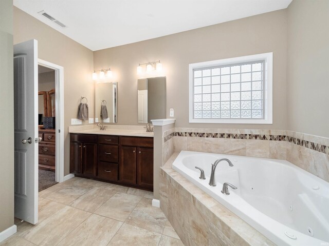 bathroom with tile patterned flooring, vanity, and tiled bath