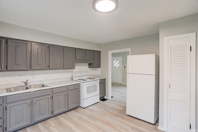 kitchen with gray cabinetry, sink, tasteful backsplash, white appliances, and light wood-type flooring