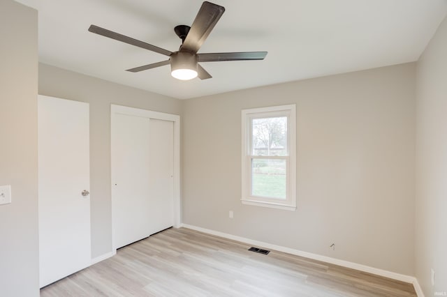 unfurnished bedroom featuring ceiling fan, light hardwood / wood-style floors, and a closet