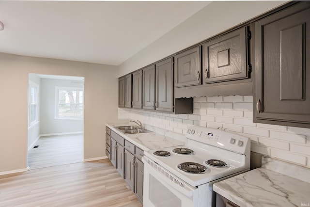 kitchen with white electric range, sink, light hardwood / wood-style flooring, light stone countertops, and tasteful backsplash