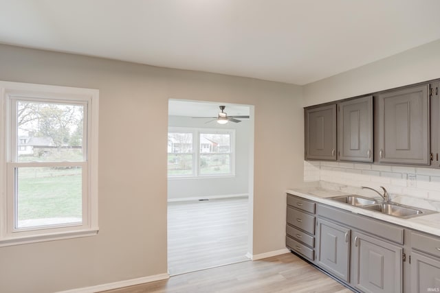 kitchen featuring backsplash, gray cabinets, light hardwood / wood-style floors, and sink