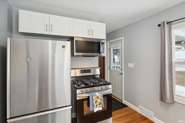 kitchen with white cabinets, appliances with stainless steel finishes, hardwood / wood-style flooring, and plenty of natural light