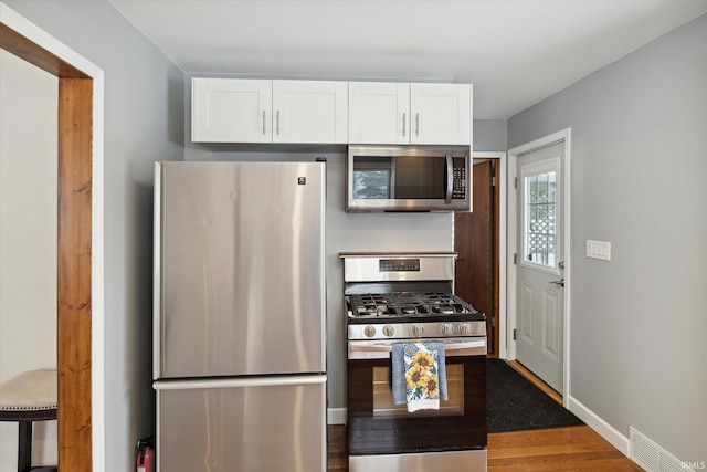 kitchen with white cabinets, stainless steel appliances, and dark hardwood / wood-style floors