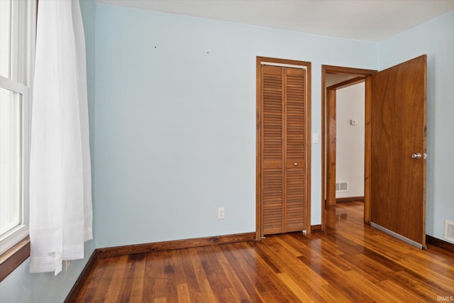 unfurnished bedroom featuring dark hardwood / wood-style flooring and a closet