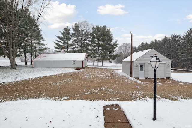 yard layered in snow featuring an outbuilding and a garage