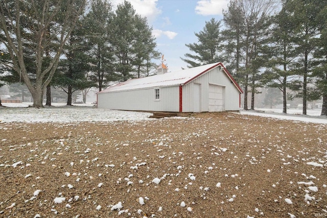 view of snow covered exterior with an outbuilding and a garage