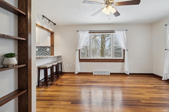 interior space with dark hardwood / wood-style flooring, rail lighting, and ceiling fan