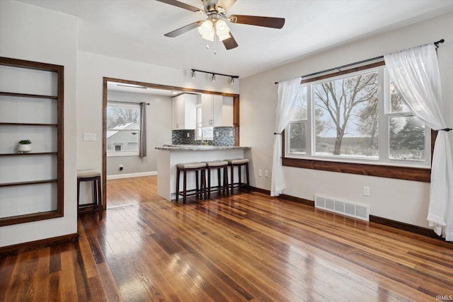 living room featuring dark hardwood / wood-style flooring, built in features, and ceiling fan