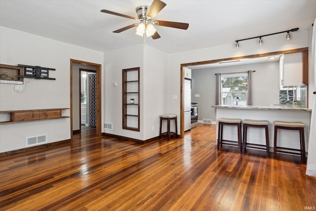 kitchen with kitchen peninsula, a kitchen breakfast bar, ceiling fan, dark hardwood / wood-style floors, and white cabinetry