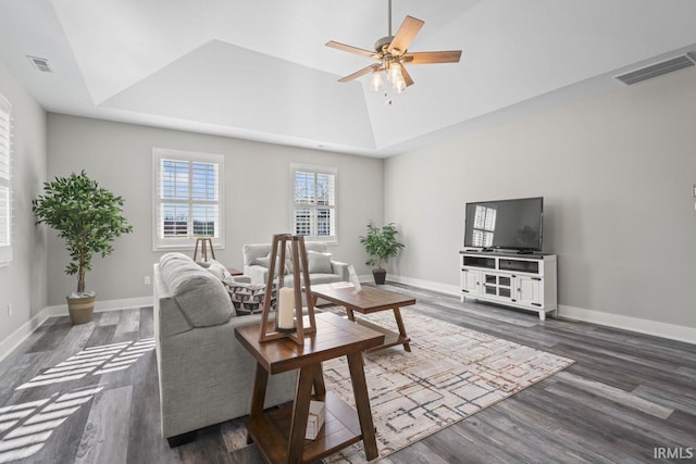 living room featuring lofted ceiling, a raised ceiling, ceiling fan, and dark wood-type flooring