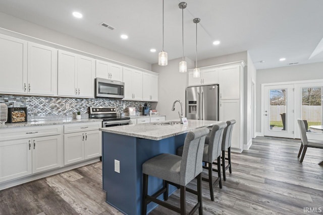 kitchen with stainless steel appliances, pendant lighting, a center island with sink, white cabinets, and dark hardwood / wood-style floors