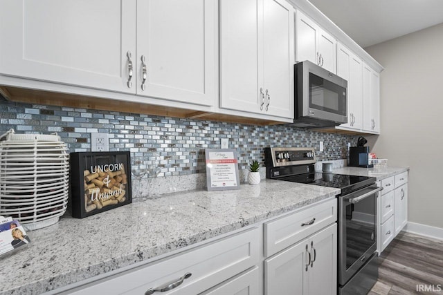 kitchen with white cabinetry, light stone countertops, dark hardwood / wood-style flooring, decorative backsplash, and appliances with stainless steel finishes