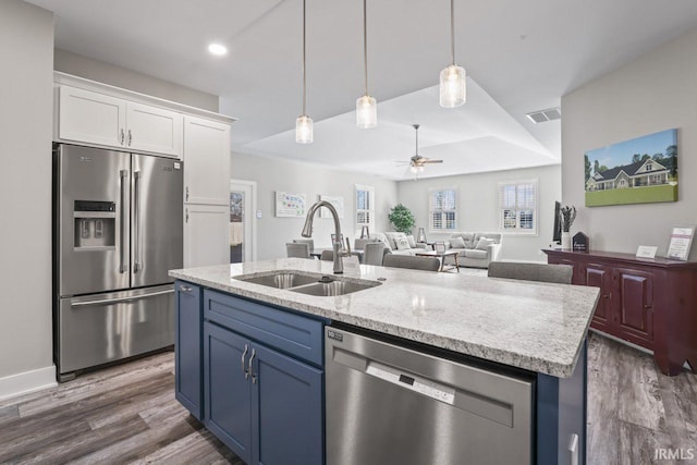 kitchen with white cabinets, a center island with sink, sink, ceiling fan, and appliances with stainless steel finishes