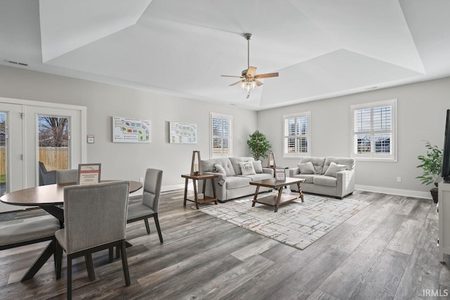 living room featuring hardwood / wood-style flooring, ceiling fan, and a raised ceiling