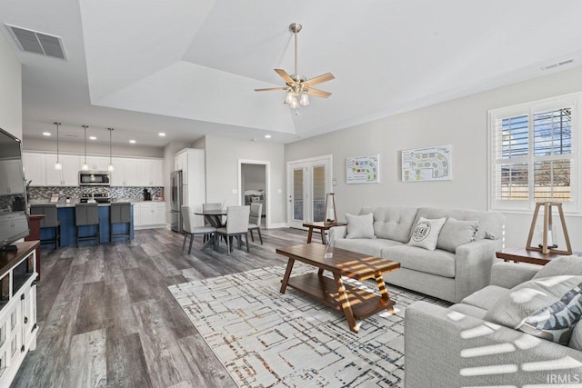 living room with hardwood / wood-style floors, vaulted ceiling, a raised ceiling, and ceiling fan