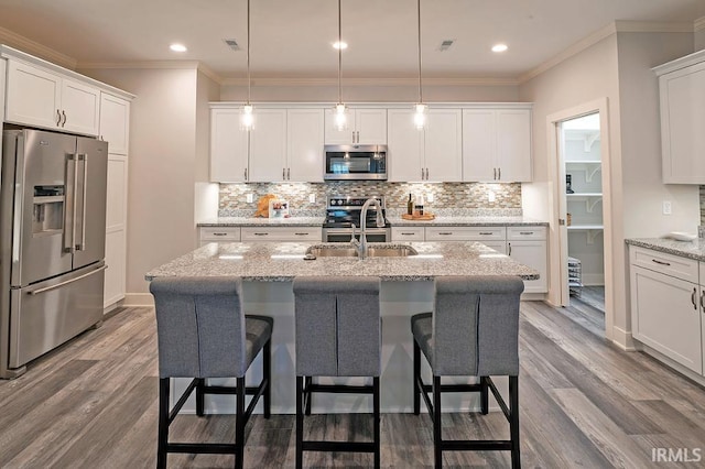 kitchen featuring light stone counters, pendant lighting, hardwood / wood-style flooring, and appliances with stainless steel finishes