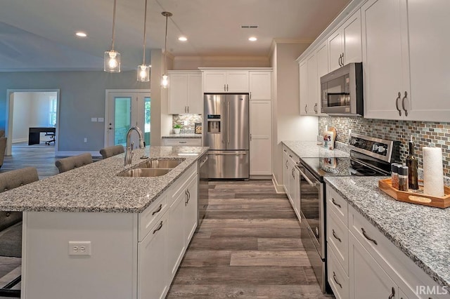 kitchen featuring a breakfast bar, stainless steel appliances, sink, white cabinetry, and an island with sink