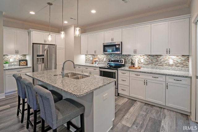 kitchen with white cabinetry, sink, light stone countertops, wood-type flooring, and appliances with stainless steel finishes