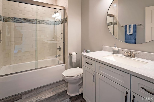 full bathroom with toilet, vanity, wood-type flooring, and combined bath / shower with glass door