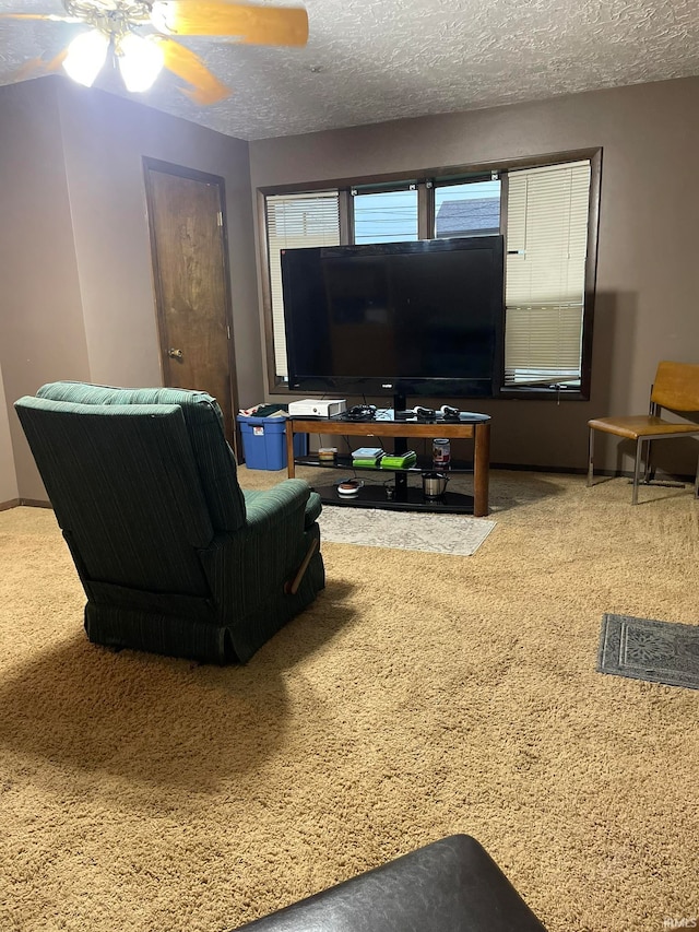 carpeted living room with ceiling fan and a textured ceiling