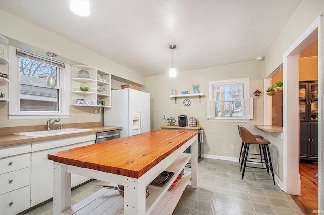 kitchen with butcher block countertops, decorative light fixtures, a healthy amount of sunlight, and white cabinets