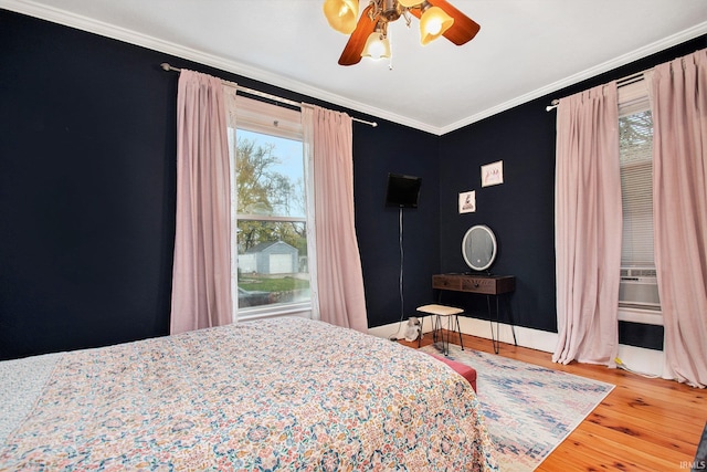 bedroom with multiple windows, ceiling fan, crown molding, and wood-type flooring