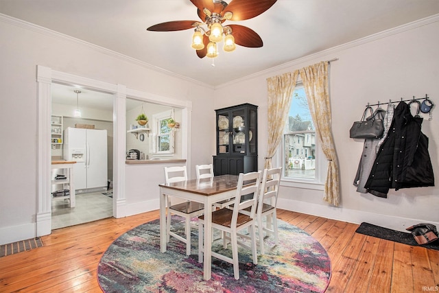 dining space with ceiling fan, ornamental molding, and light hardwood / wood-style flooring