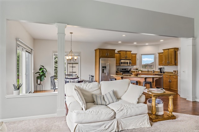 living room with a wealth of natural light, sink, light wood-type flooring, and a notable chandelier