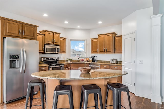 kitchen with a kitchen breakfast bar, a center island, dark hardwood / wood-style floors, and appliances with stainless steel finishes