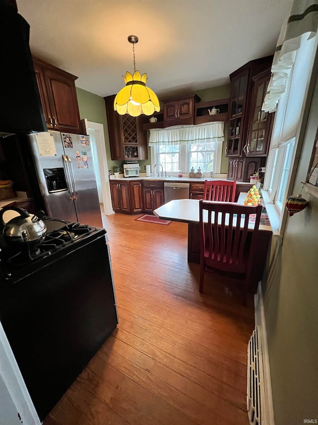 kitchen with hanging light fixtures, sink, light hardwood / wood-style floors, and appliances with stainless steel finishes