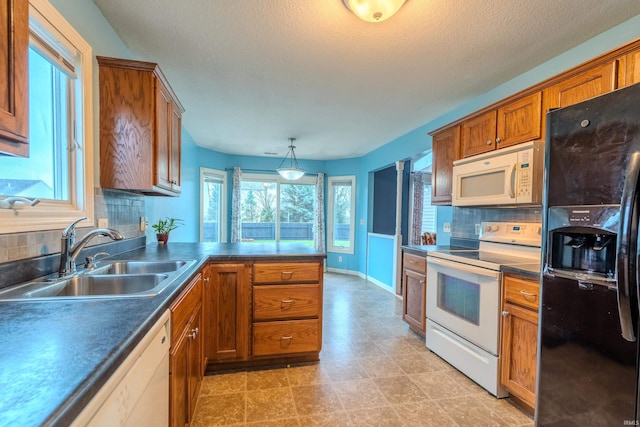 kitchen with pendant lighting, white appliances, sink, and tasteful backsplash